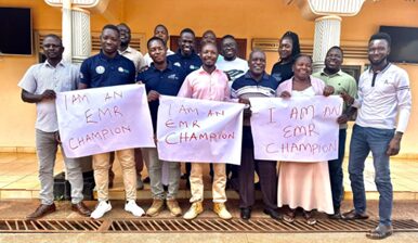 A group of men and women stand outside a bulding holding signs that read "I am an EMR champion."